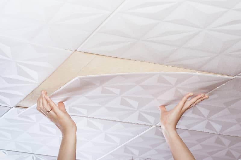 Installing acoustic ceiling tiles directly on the ceiling.