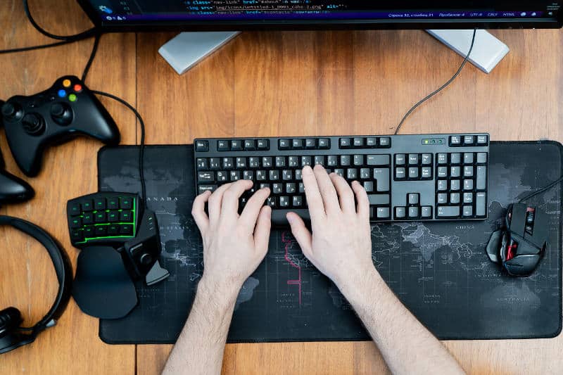 A pair of hands deftly typing on a quiet keyboard, placed on a black desk mat.